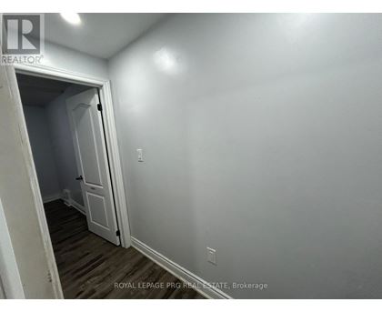 A white door is open to a room with a wooden floor.