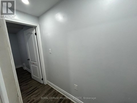 A white door is open to a room with a wooden floor.