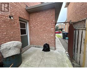 A black bag sits on a concrete walkway outside a brick building.