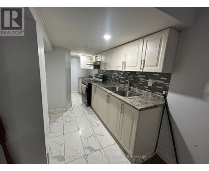 A kitchen with white cabinets and a black and white tiled floor.