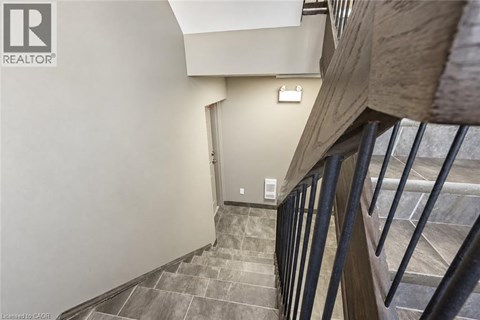 A staircase with a metal railing and a light switch on the wall.