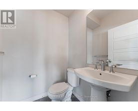 A white bathroom with a toilet, sink and mirror.