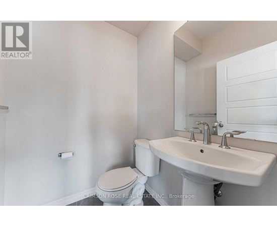 A white bathroom with a toilet, sink and mirror.