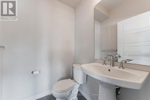 A white bathroom with a toilet, sink and mirror.