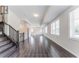 A spacious room with wooden floors and a staircase leading to the upper level.