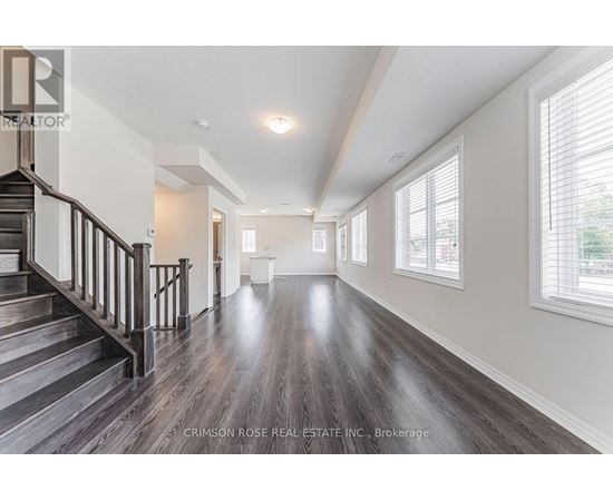 A spacious room with wooden floors and a staircase leading to the upper level.