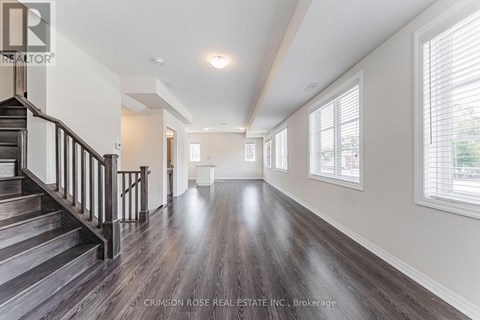 A spacious room with wooden floors and a staircase leading to the upper level.