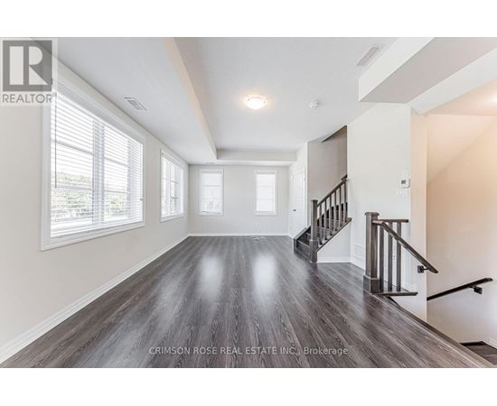 A spacious room with wood flooring and a staircase.