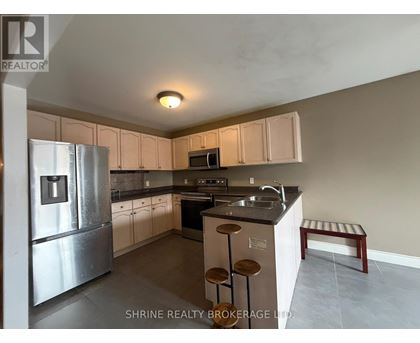 A kitchen with a refrigerator, microwave, oven, and sink.