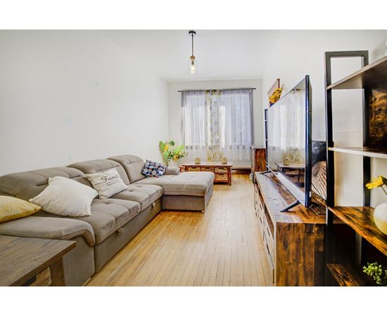 A living room with a grey sofa and a wooden floor.