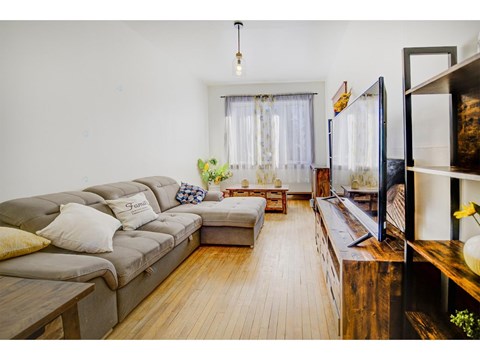 A living room with a grey sofa and a wooden floor.