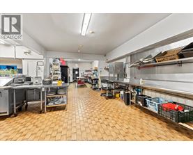 A large commercial kitchen with wooden floors and stainless steel appliances.