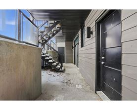 A black door is on the right side of a concrete wall.