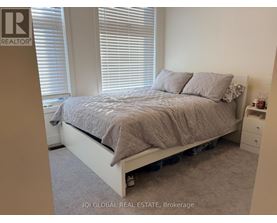 A bedroom with a bed, nightstand, and window with blinds.