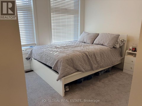 A bedroom with a bed, nightstand, and window with blinds.