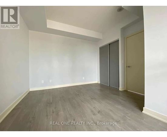 A room with a grey floor and a white wall with a door on the right side.