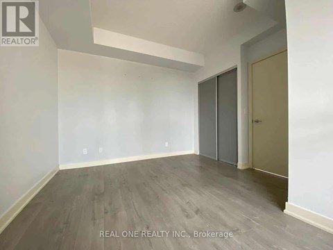 A room with a grey floor and a white wall with a door on the right side.