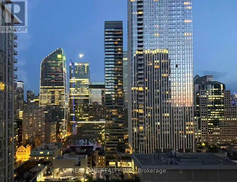 A cityscape at dusk with buildings illuminated from within.
