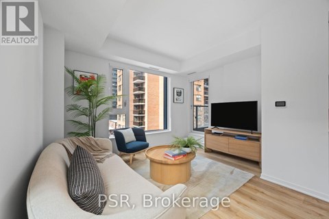 A living room with a couch, a chair, a coffee table, and a television.