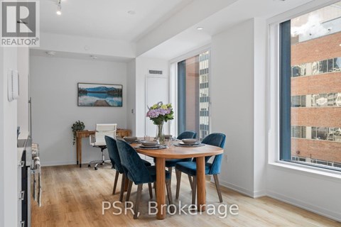 A dining room with a table set for four and a painting on the wall.