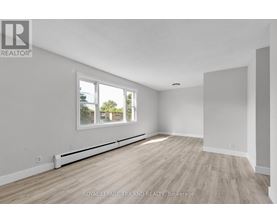 A white room with a window and wooden flooring.