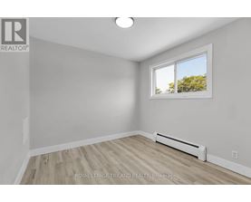 A white room with a window and a radiator on the floor.