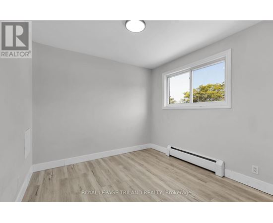 A white room with a window and a radiator on the floor.