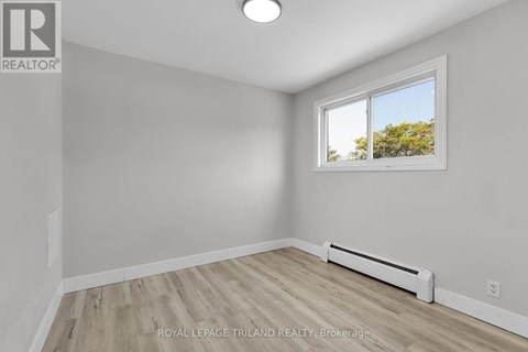 A white room with a window and a radiator on the floor.