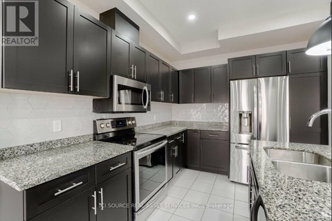 A modern kitchen with black cabinets and granite countertops.