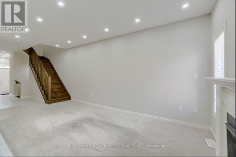 A spacious room with a staircase and a fireplace.