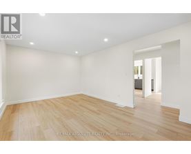 A spacious room with wooden flooring and white walls.