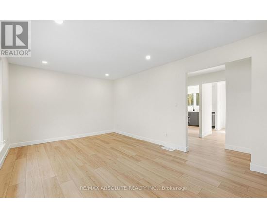 A spacious room with wooden flooring and white walls.