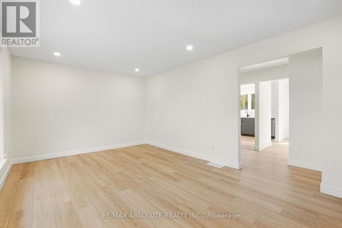 A spacious room with wooden flooring and white walls.