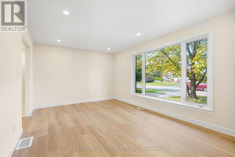 A room with a window showing a view of a street with cars and trees.
