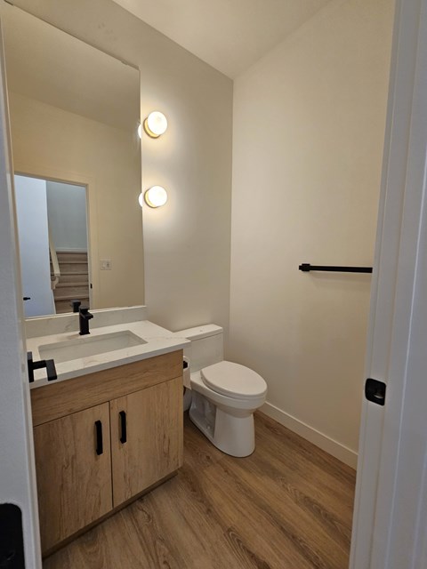 A white toilet sits in a bathroom next to a sink and mirror.