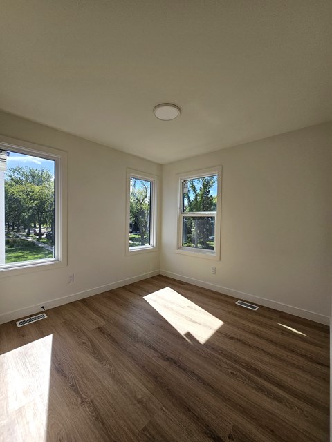 A room with wooden floors and two windows.