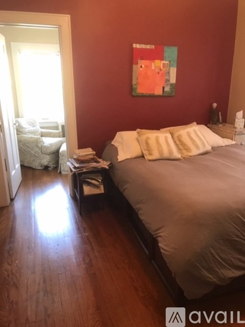 A bedroom with a bed, a chair, and a painting on the wall.