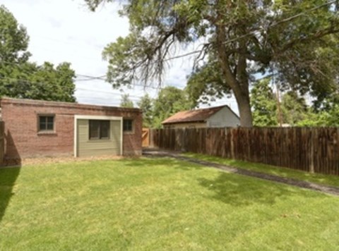 A backyard with a fence and a small building.