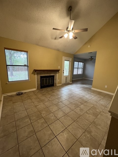 A living room with a fireplace and a ceiling fan.