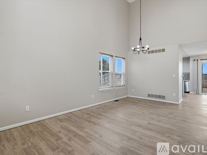 A spacious room with wooden flooring and a chandelier hanging from the ceiling.