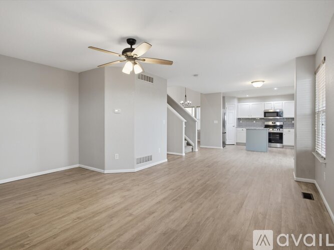 A spacious living room with a ceiling fan and lighting fixture.