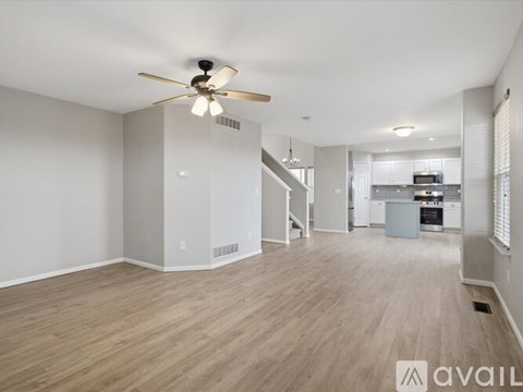 A spacious living room with a ceiling fan and lighting fixture.