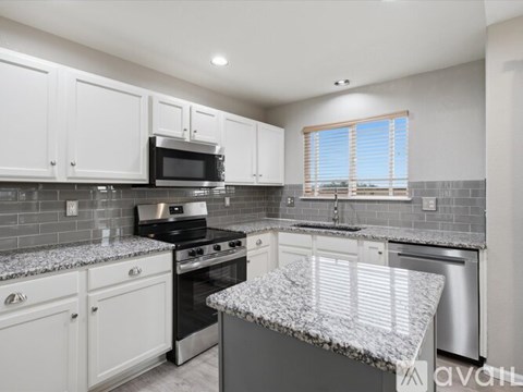 A kitchen with white cabinets and a granite countertop.