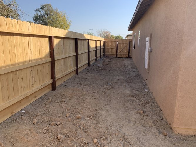 A wooden fence runs along the side of a building.