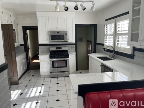 A kitchen with white cabinets and a black and white checkered floor.
