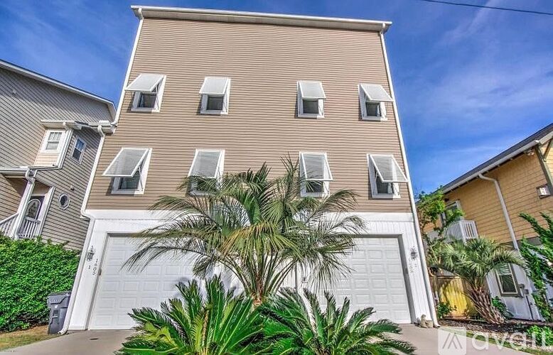 A two-story building with a garage and a palm tree in front.