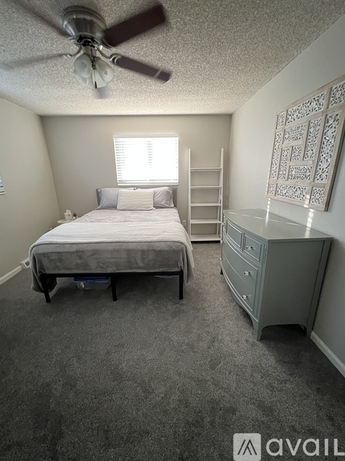 A bedroom with a bed, dresser, and ceiling fan.