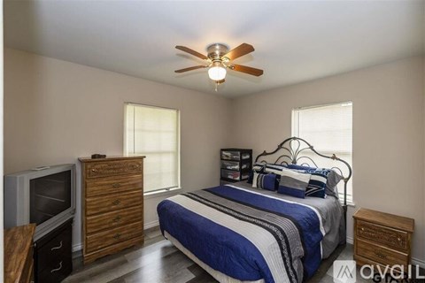 A bedroom with a bed, dresser, and ceiling fan.