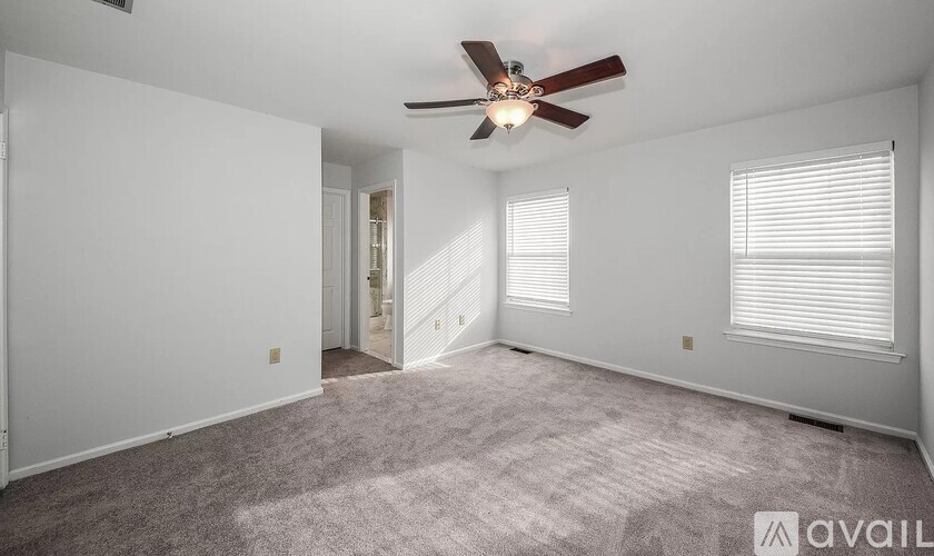A spacious room with a ceiling fan and carpeted floor.