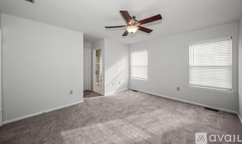 A spacious room with a ceiling fan and carpeted floor.
